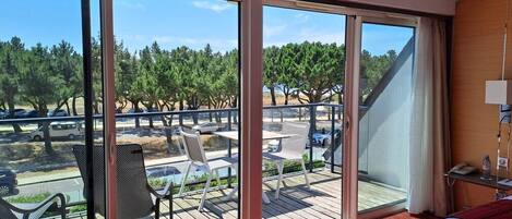 A hotel room with a large sliding glass door leading to an outdoor deck with chairs and tables.