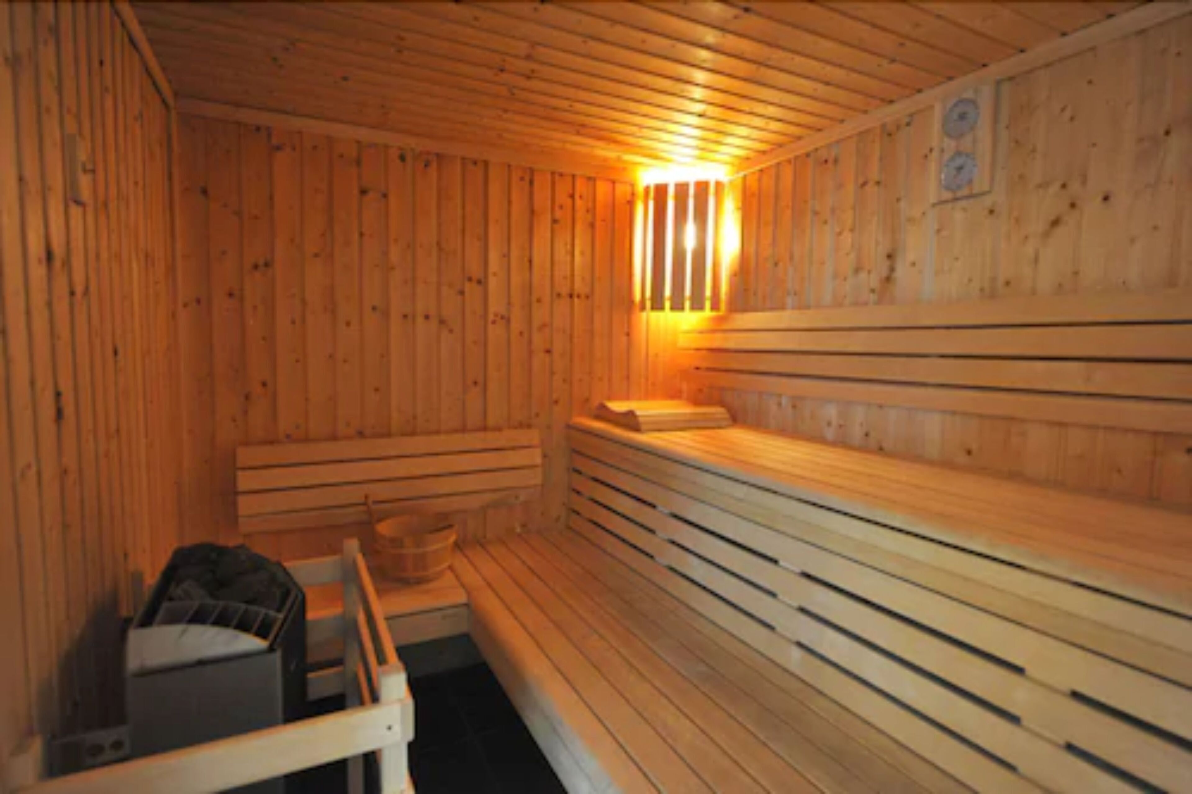 A sauna with wooden walls and benches, a bench with a towel, and a small table with a bowl.