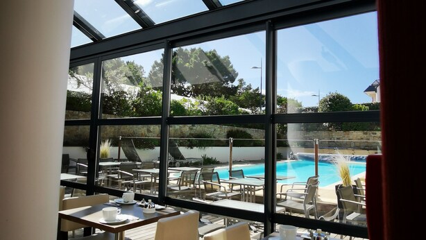 Un restaurante con terraza al aire libre y vistas a una piscina.