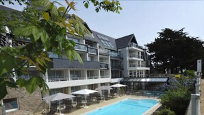 Un hotel moderno con piscina, mobiliario exterior y fachada de piedra.