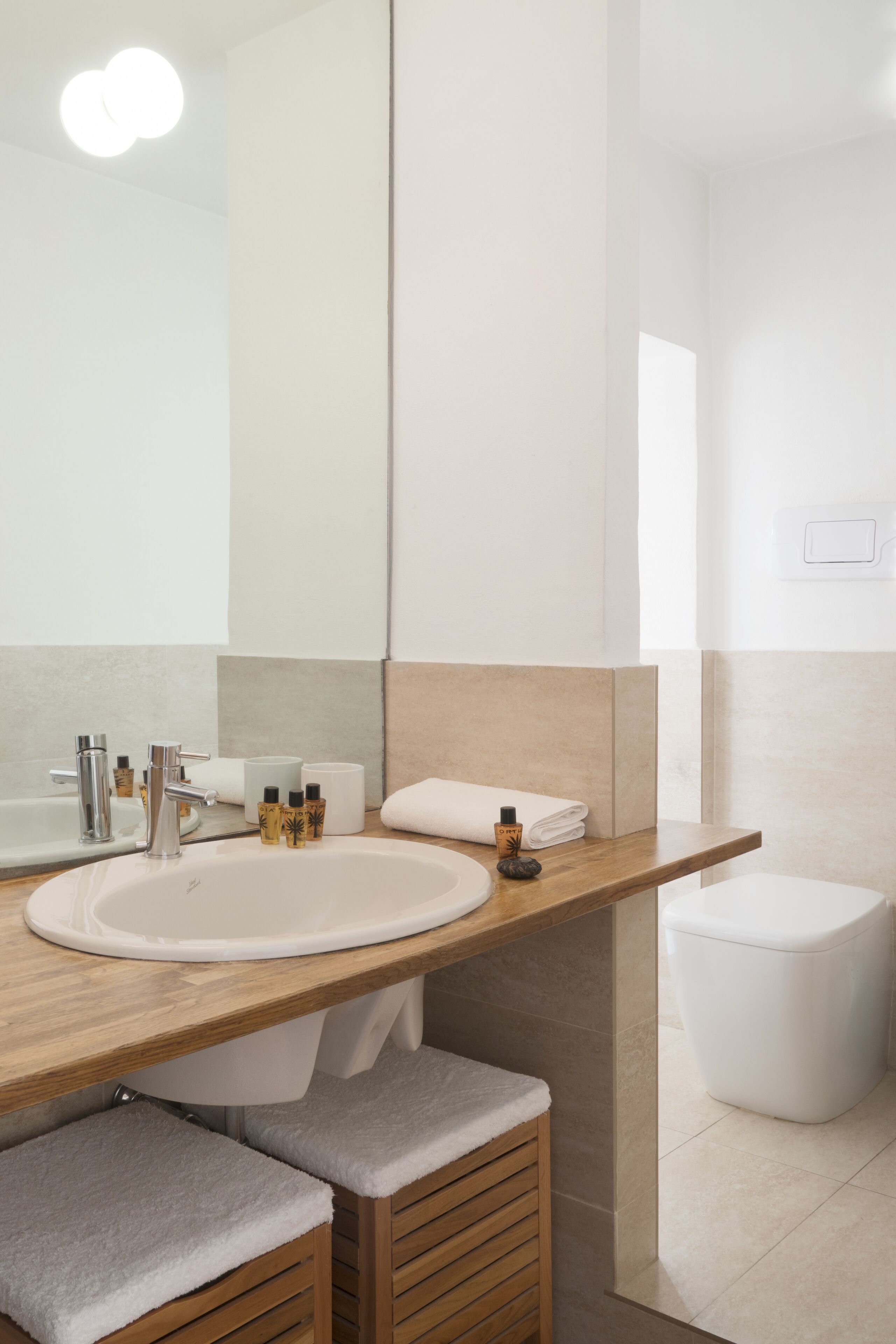 A modern bathroom with a large mirror, a sink, and a toilet.