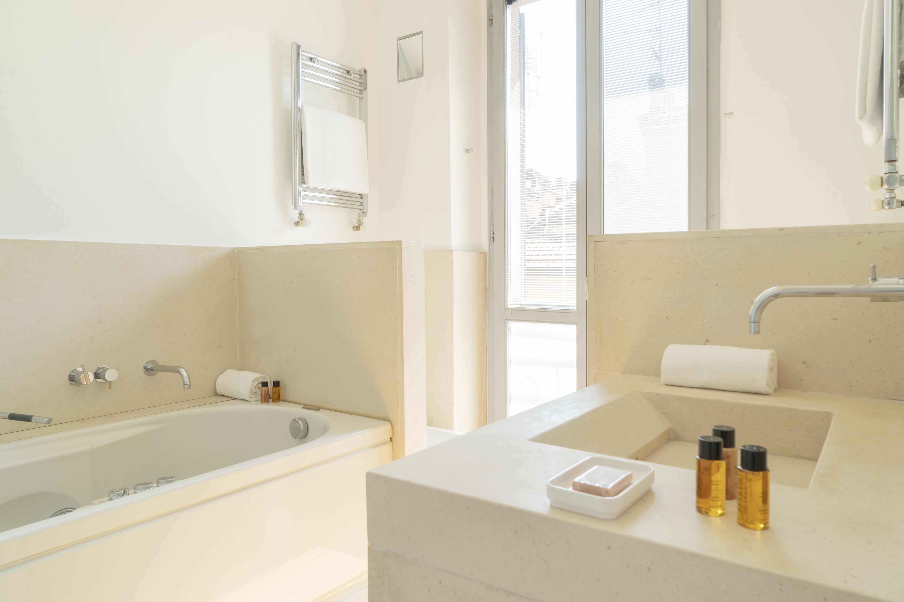 Un baño moderno con bañera, lavamanos con espejo y ventana que proporciona luz natural.
