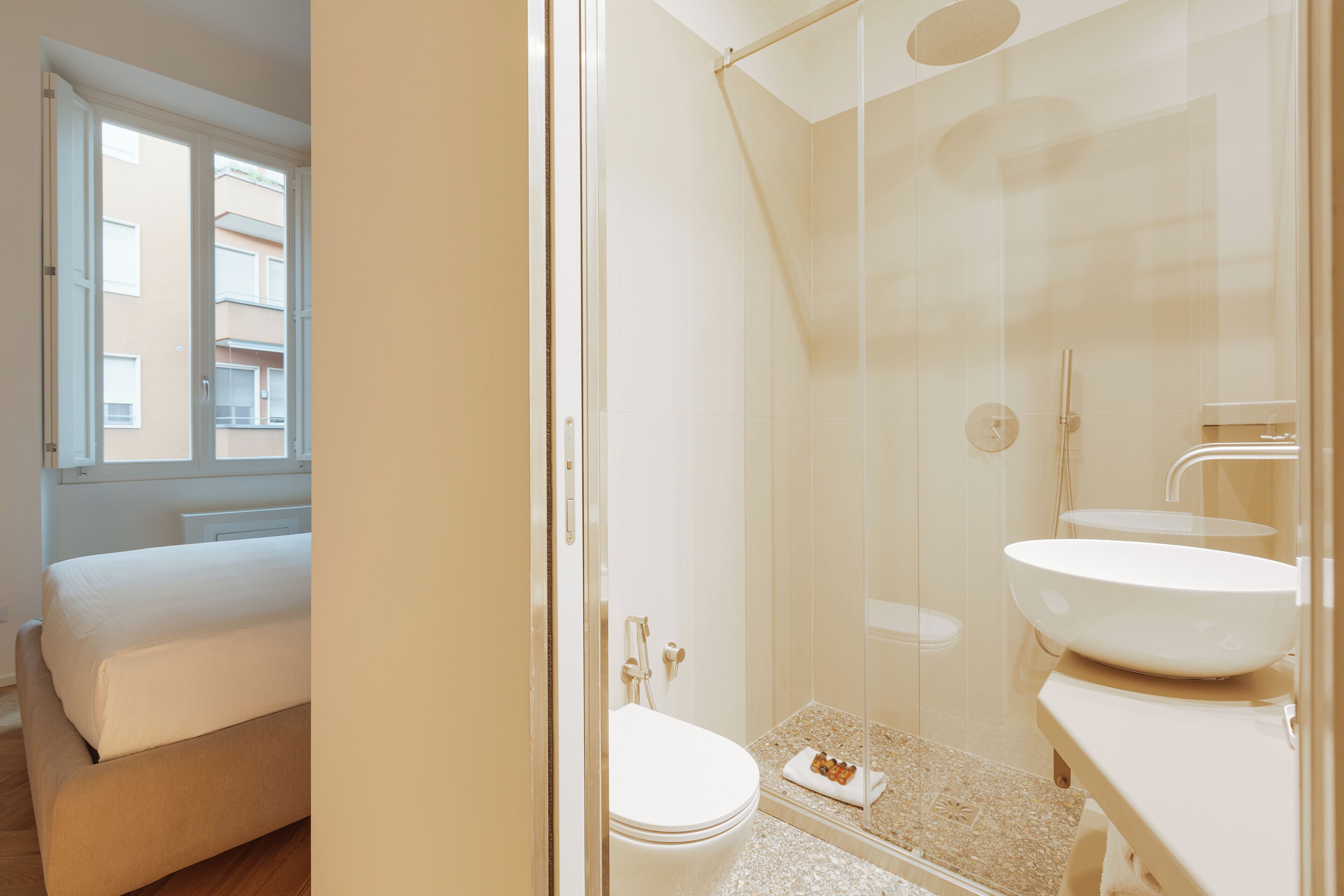 A modern bathroom with a glass shower enclosure, a double sink, and a toilet.
