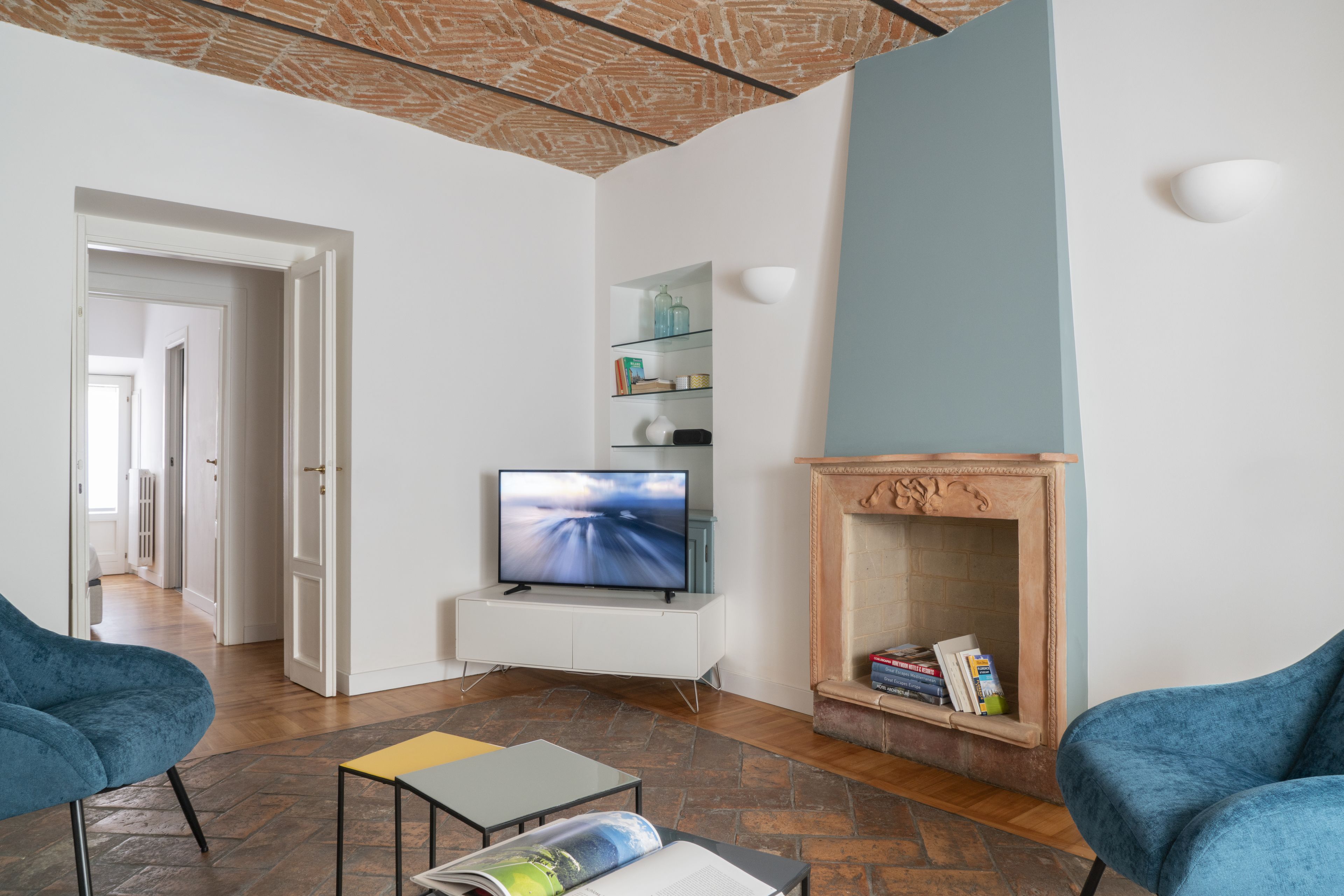 Una sala de estar moderna con televisor, sillones azules, chimenea y estantería.