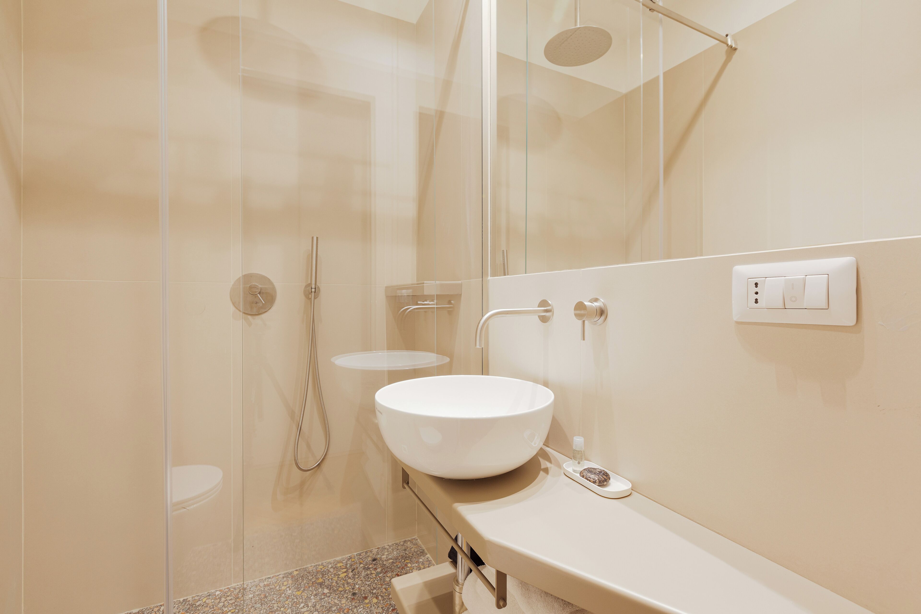 A modern bathroom with a glass-enclosed shower, a white sink, and a mirror.