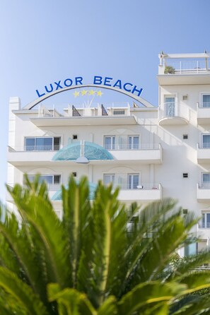 Un hotel de varios pisos con balcones y un letrero que dice "LUXOR BEACH".