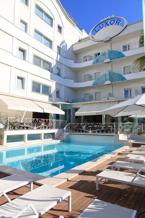 Een buitenzwembad, parasols bij het zwembad en ligstoelen