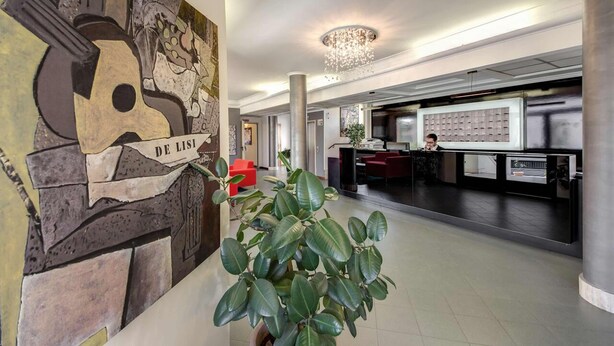 A lobby with a reception desk, a chandelier, and a large abstract artwork. - Hotel Alba Roma (Rome)