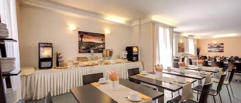 Un comedor con varias mesas y sillas, una barra de buffet y obras de arte colgadas en la pared.