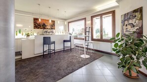 A modern kitchen with a central island, bar stools, and a large window. - Hotel Alba Roma (Rome)