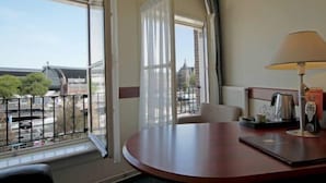 Ein Hotelzimmer mit Balkon, einem Tisch, einer Lampe und Blick auf die Stadt.