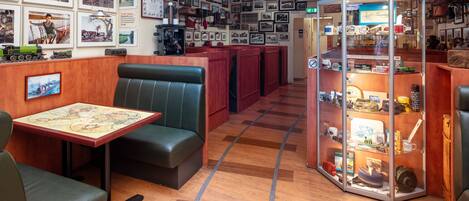 Ein Restaurant mit Holzböden, dunkelgrünen Ledersitzbänken und einer Wand mit gerahmten Fotos.