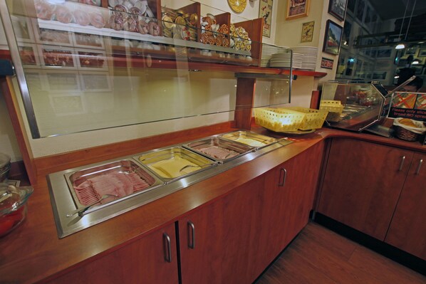 A buffet counter with various food items and a glass display case. - A Train Hotel (Amsterdam)