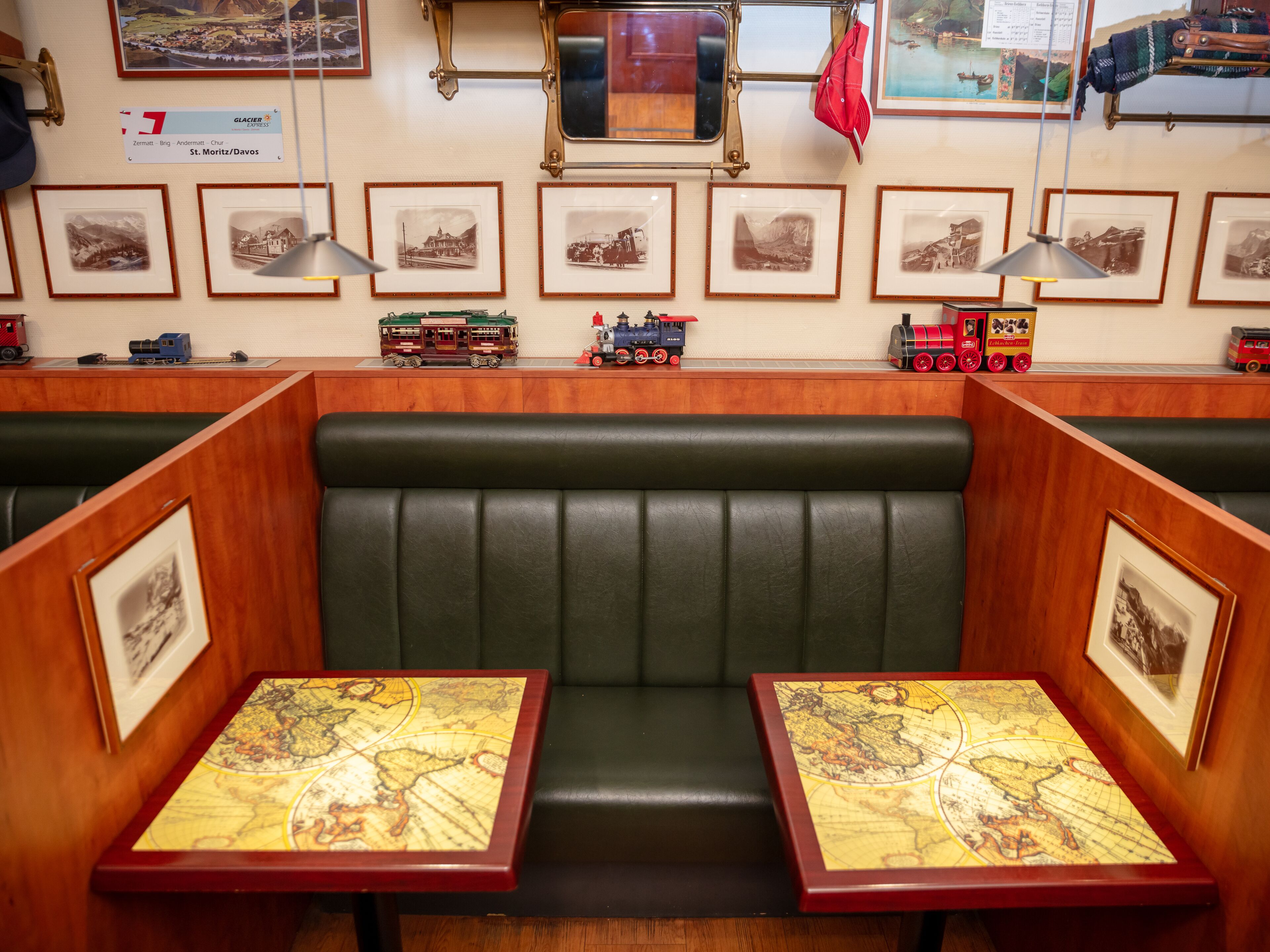 Een restaurant met een zitgedeelte met geïsoleerde hokjes, een tentoonstelling van modeltreinen en ingelijste foto's aan de muren.