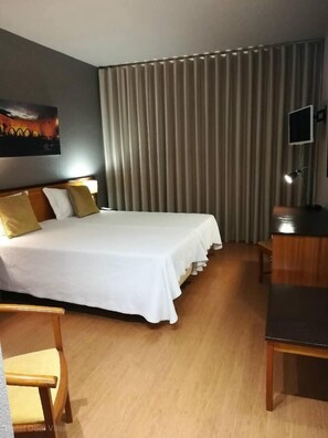 A hotel room with a large bed, a desk, a chair, and a TV. - Hotel Dom Vilas (Braga)