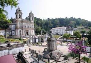 A historic church with a bell tower, a statue, and a well-maintained garden. - Hotel Dom Vilas (Braga)