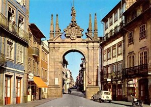 A street with an ornate archway, buildings on either side, and a parked car. - Hotel Dom Vilas (Braga)
