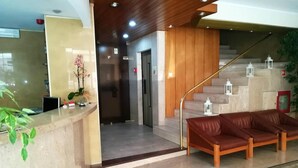 A reception area with a reception desk, a staircase, and a leather sofa. - Hotel Dom Vilas (Braga)