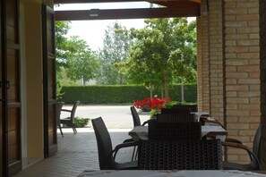 An outdoor patio with wicker furniture and a view of a road and greenery. - Antica Ravenna Residence (Ravenna)