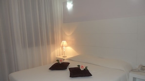 Una habitación de hotel con una cama, una lámpara de noche y un teléfono en la mesita de noche.