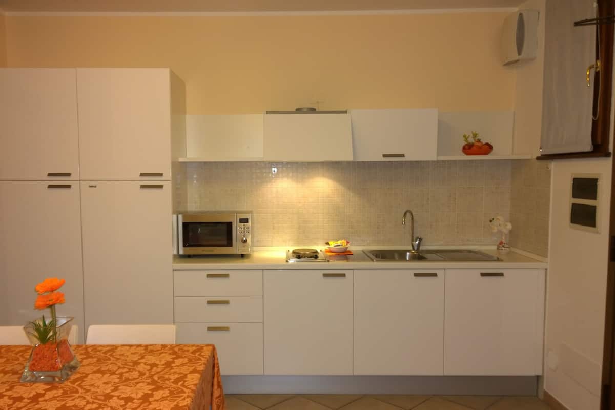 A compact kitchen with white cabinets, a microwave, a sink, and a small dining area with a table and chairs.
