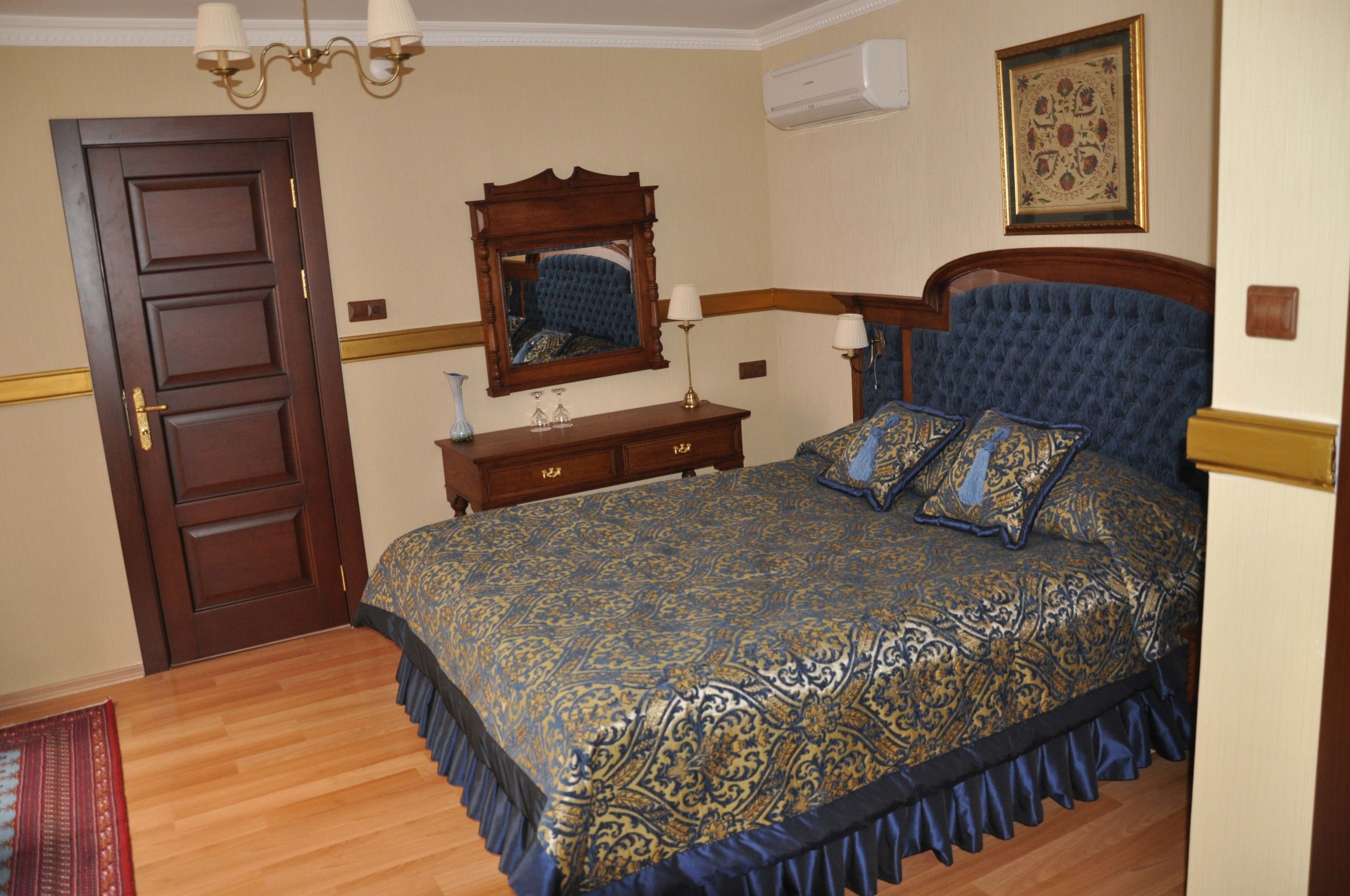 A bedroom with a large bed, a wooden dresser, a mirror, and a chandelier.