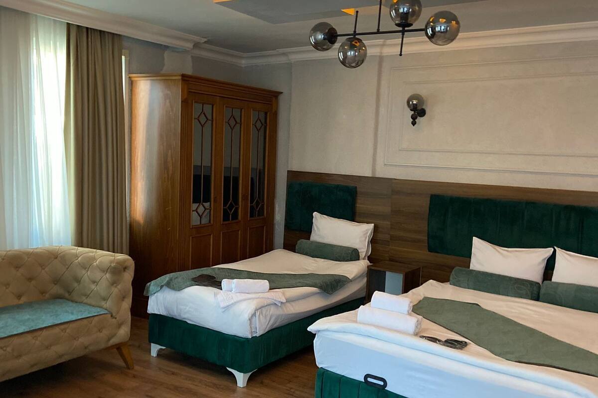 Une chambre d’hôtel avec deux lits, un canapé et une armoire en bois.