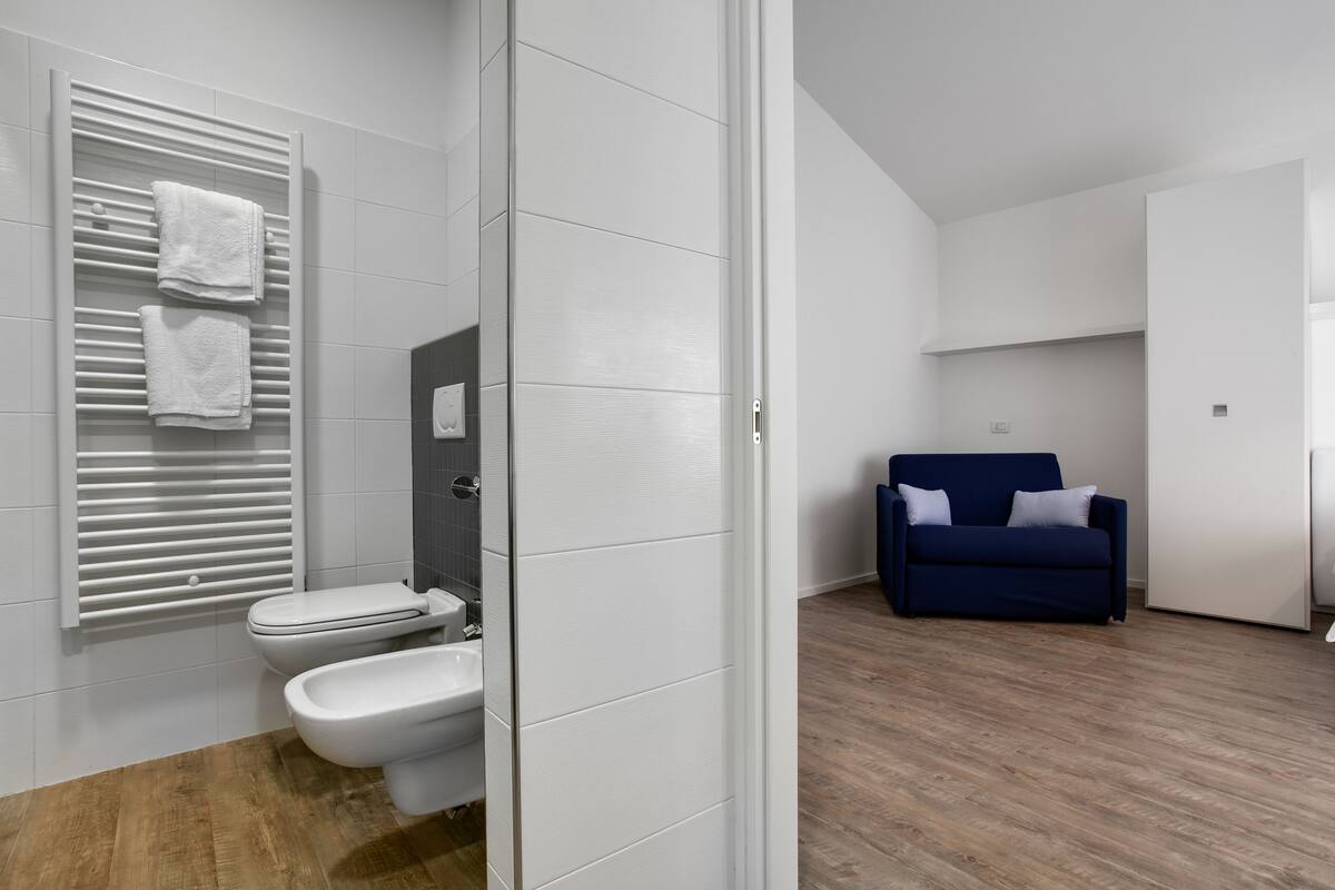 A modern bathroom with a toilet, bidet, and towel rack.