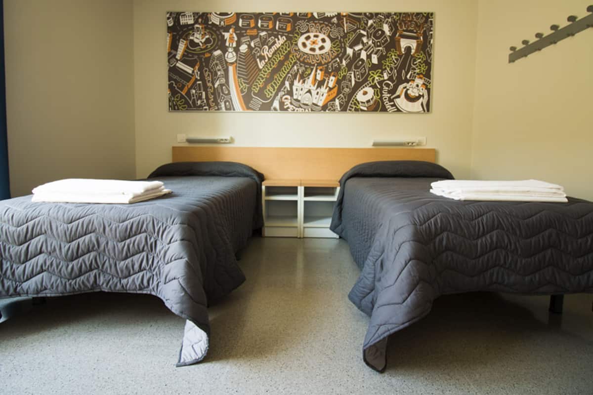 Ett hotellrum med två sängar, en stor väggmålning och en gitarr som hänger på väggen.