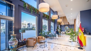 Un moderno vestíbulo de hotel con ventanas amplias, un mostrador de recepción y una bandera.