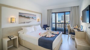Habitación de hotel con cama, escritorio, silla, teléfono y un cuadro de playa.