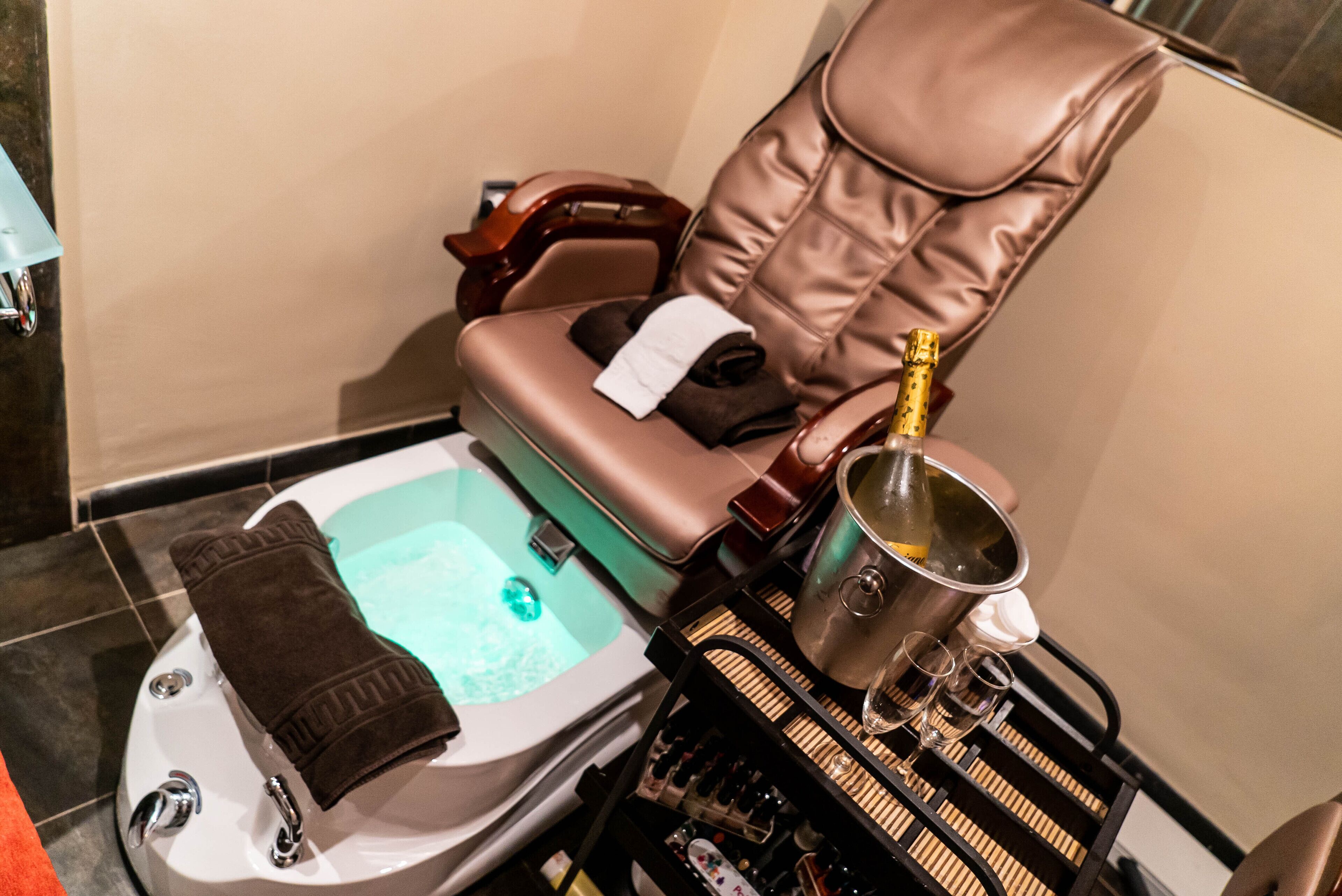 Een massagestoel, een bubbelbad en een minibar met flessen en glazen.