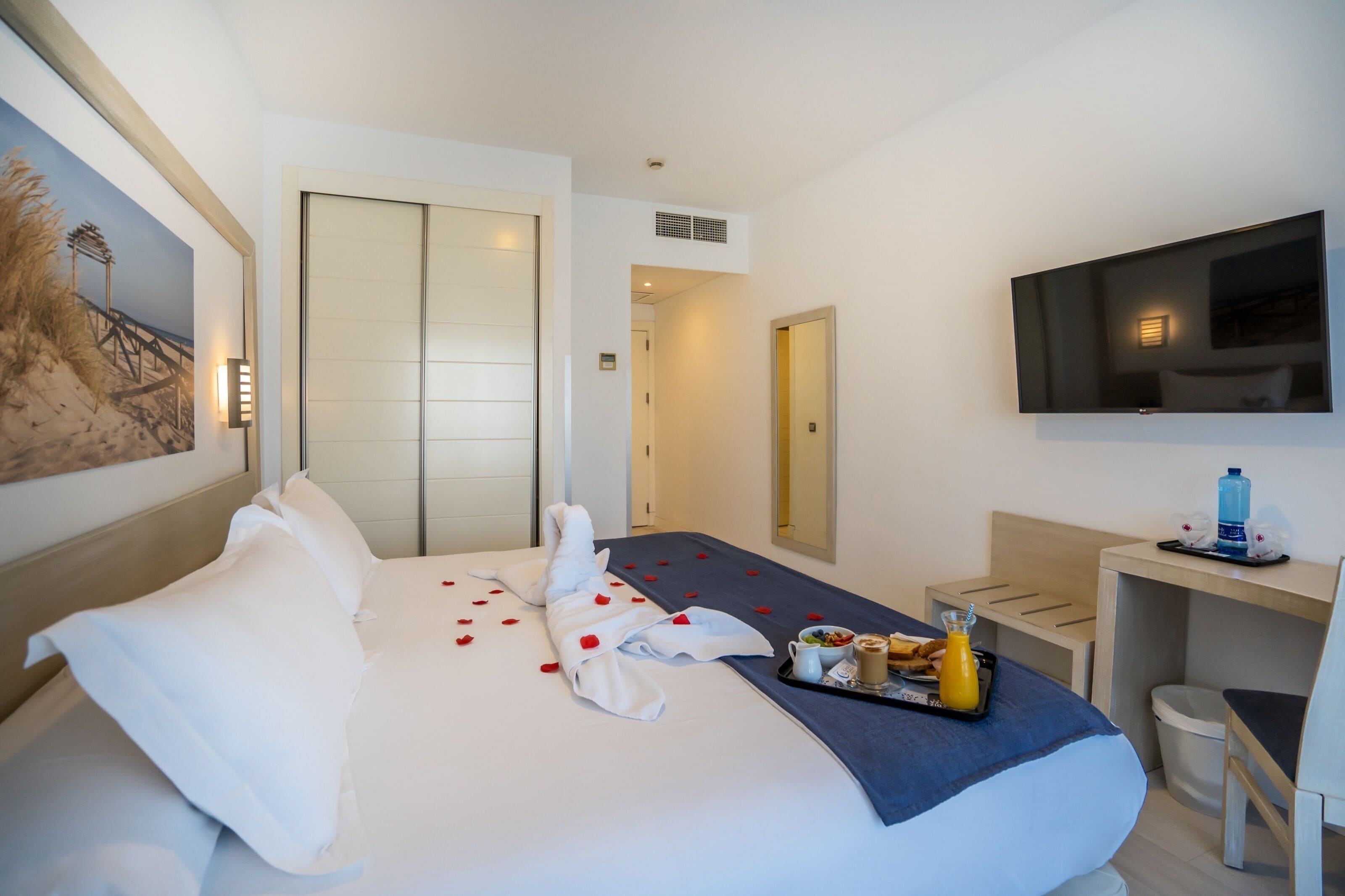 Ein Hotelzimmer mit Bett, Fernseher, Schreibtisch und Bad.