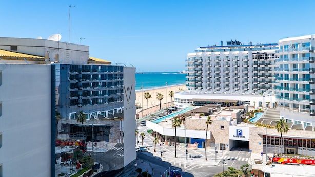 Un hotel moderno con piscina, vista a la playa y aparcamiento.