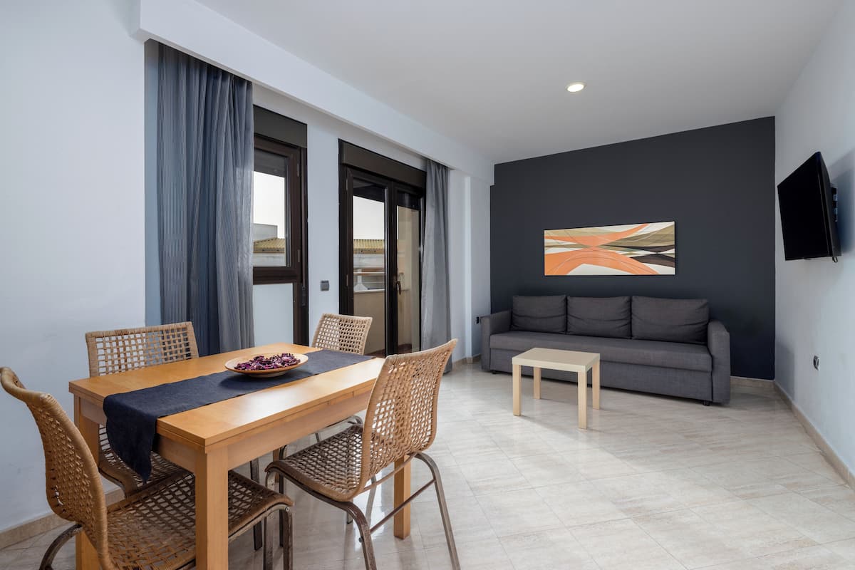 A modern living room with a dining area, featuring a sofa, a coffee table, and a dining table with chairs.