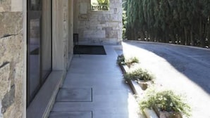 A stone building with a covered outdoor area, a sign indicating a hotel, and a row of tall trees. - Villa Luisa (Todi)