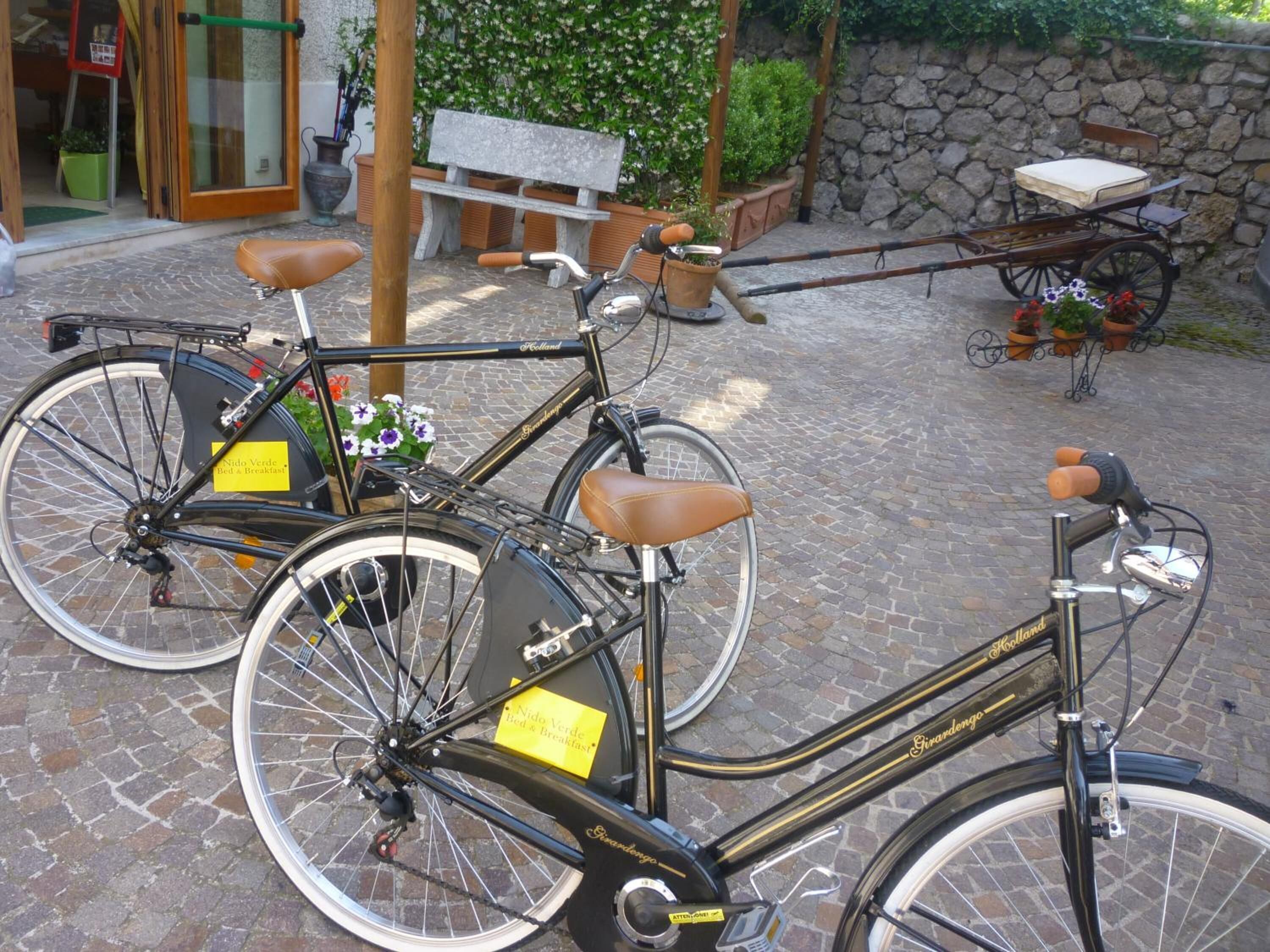 A bicycle with a bed and breakfast sign attached, parked on a cobblestone path.