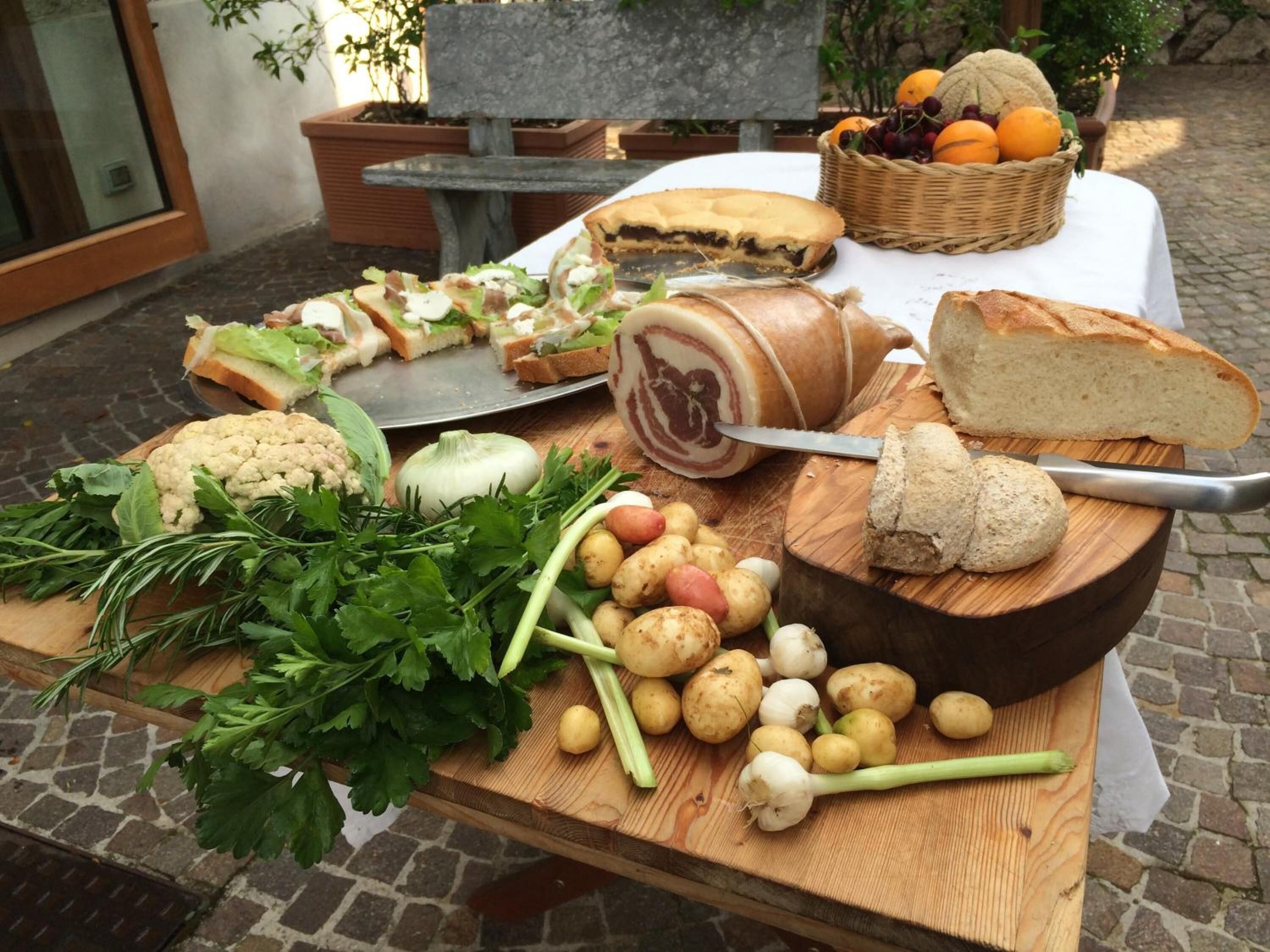 A wooden table with various food items including bread, cheese, and vegetables.