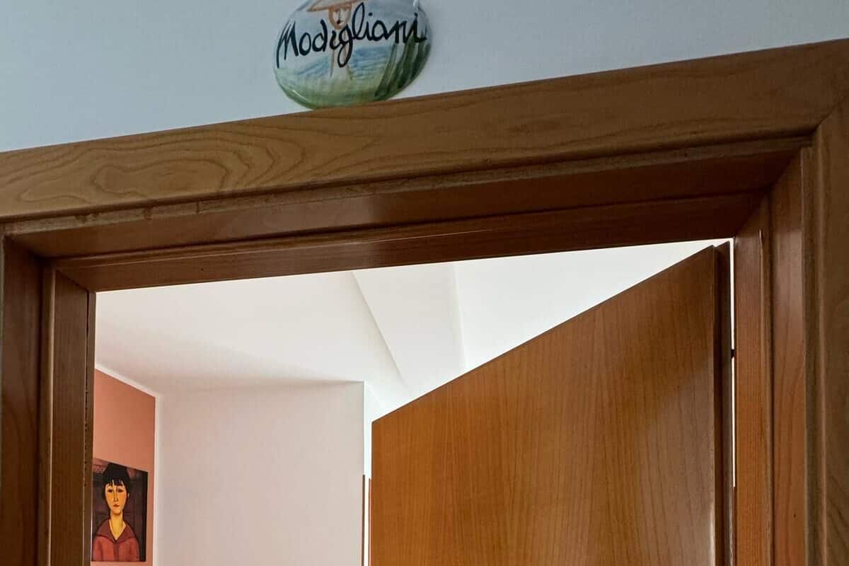 A hotel room with two beds, a wooden door, and a sign indicating a room for sale.