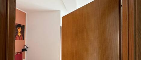 Een hotelkamer met twee bedden, een houten deur en een bordje dat aangeeft dat de kamer te koop staat.