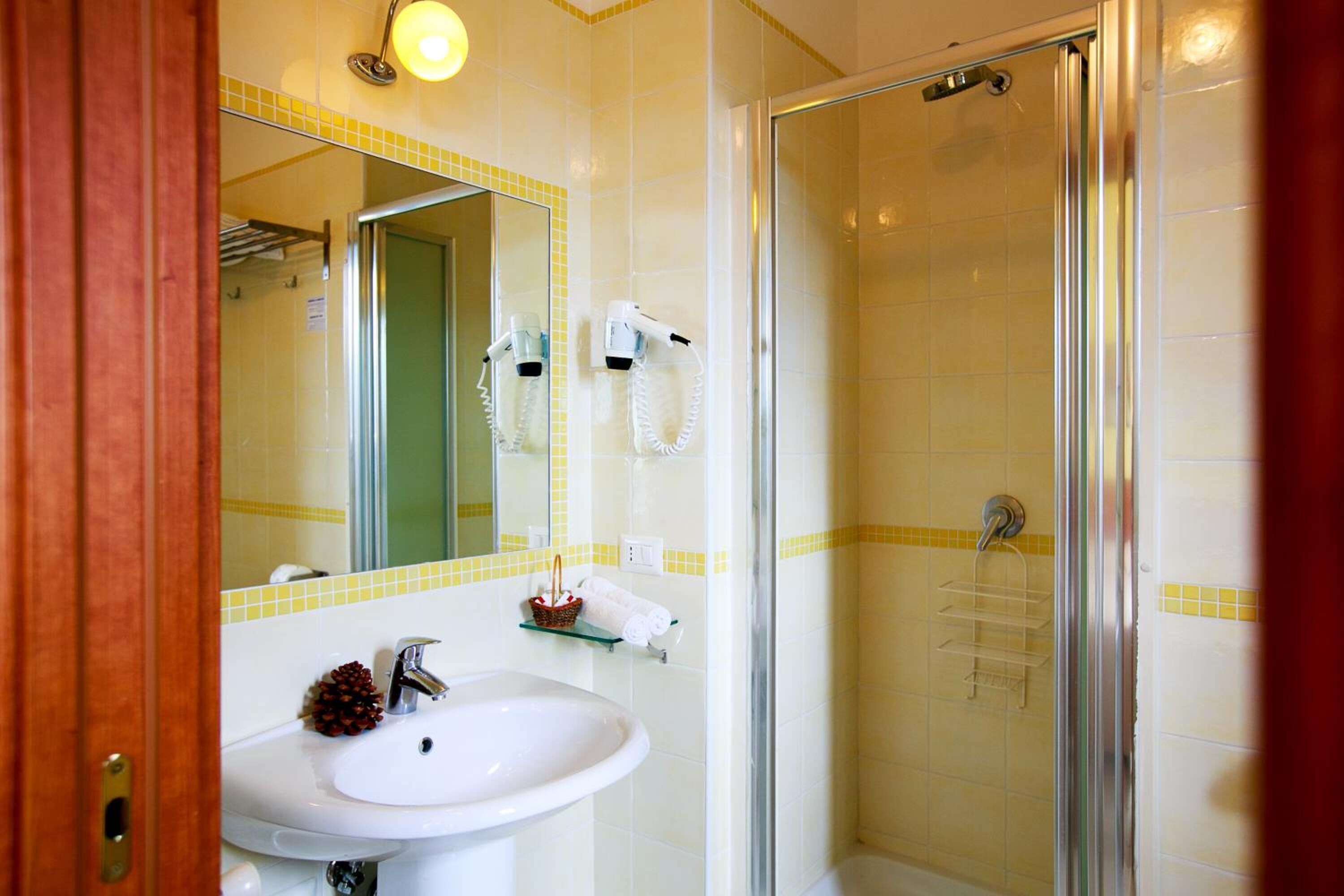 Une salle de bain équipée d’un lavabo, d’un miroir, de sèche-cheveux et d’une douche.