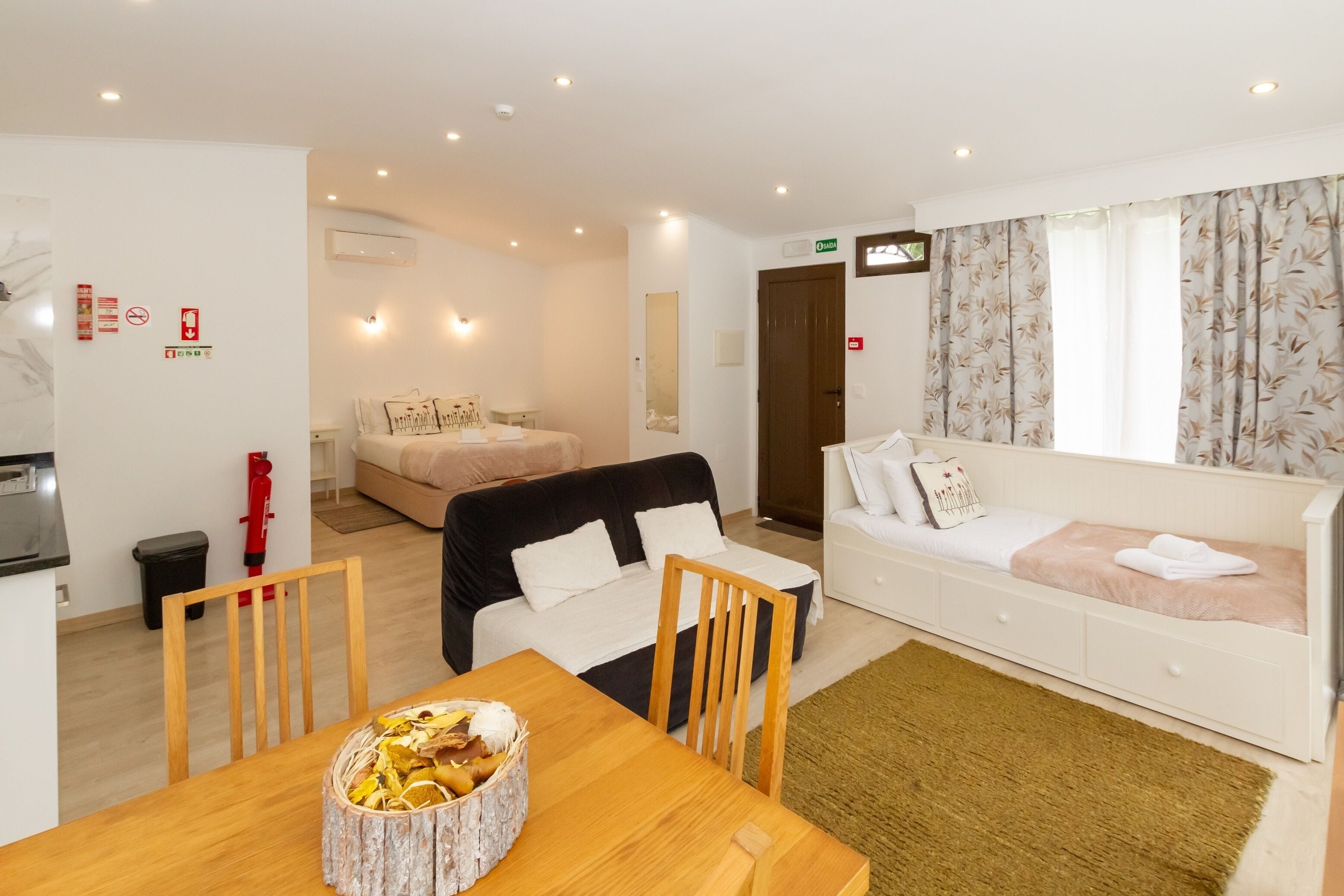 Une chambre d’hôtel moderne comprenant un coin repas, un canapé, un lit et une petite cuisine.
