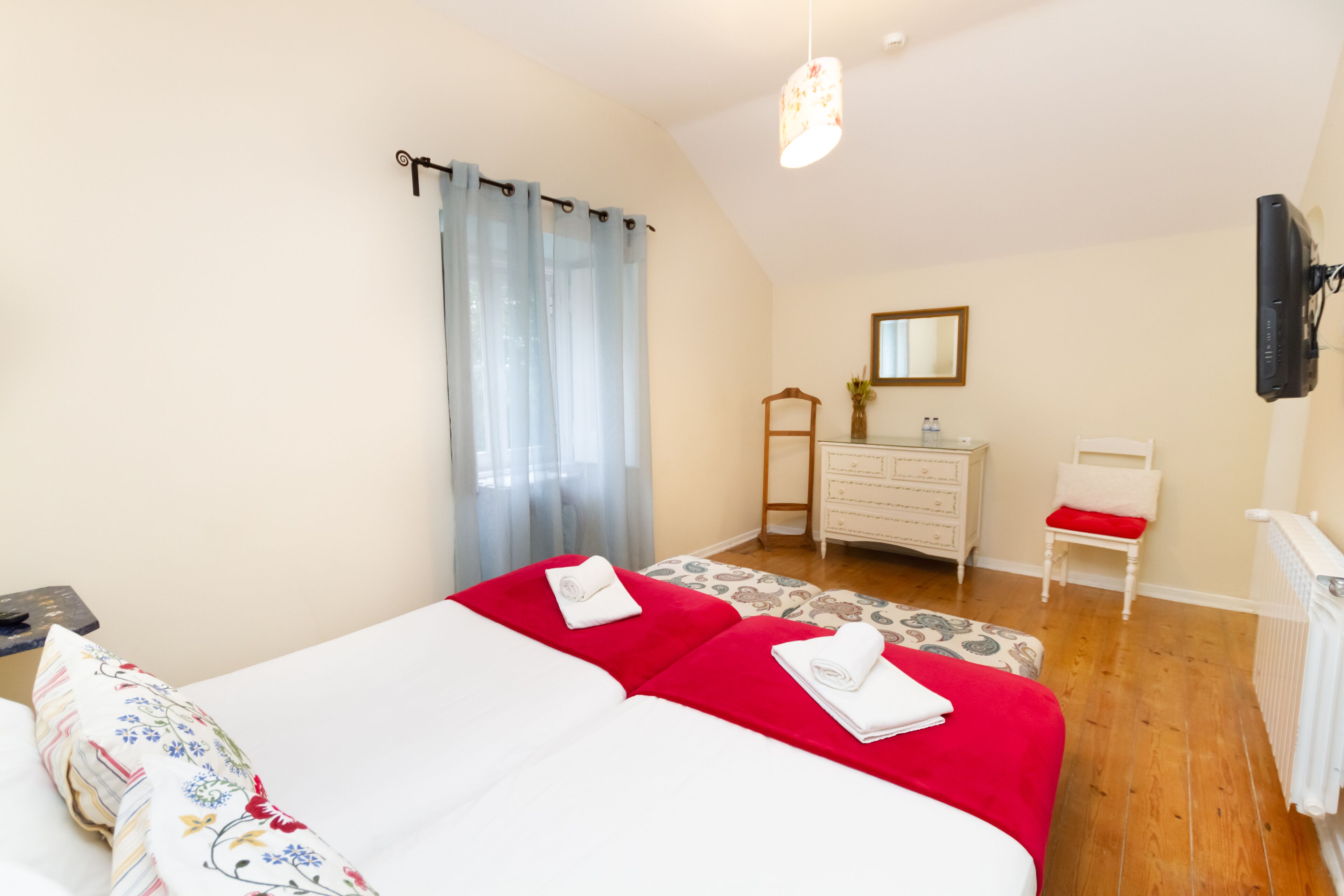 A bedroom with two beds, a dresser, a chair, and a television.