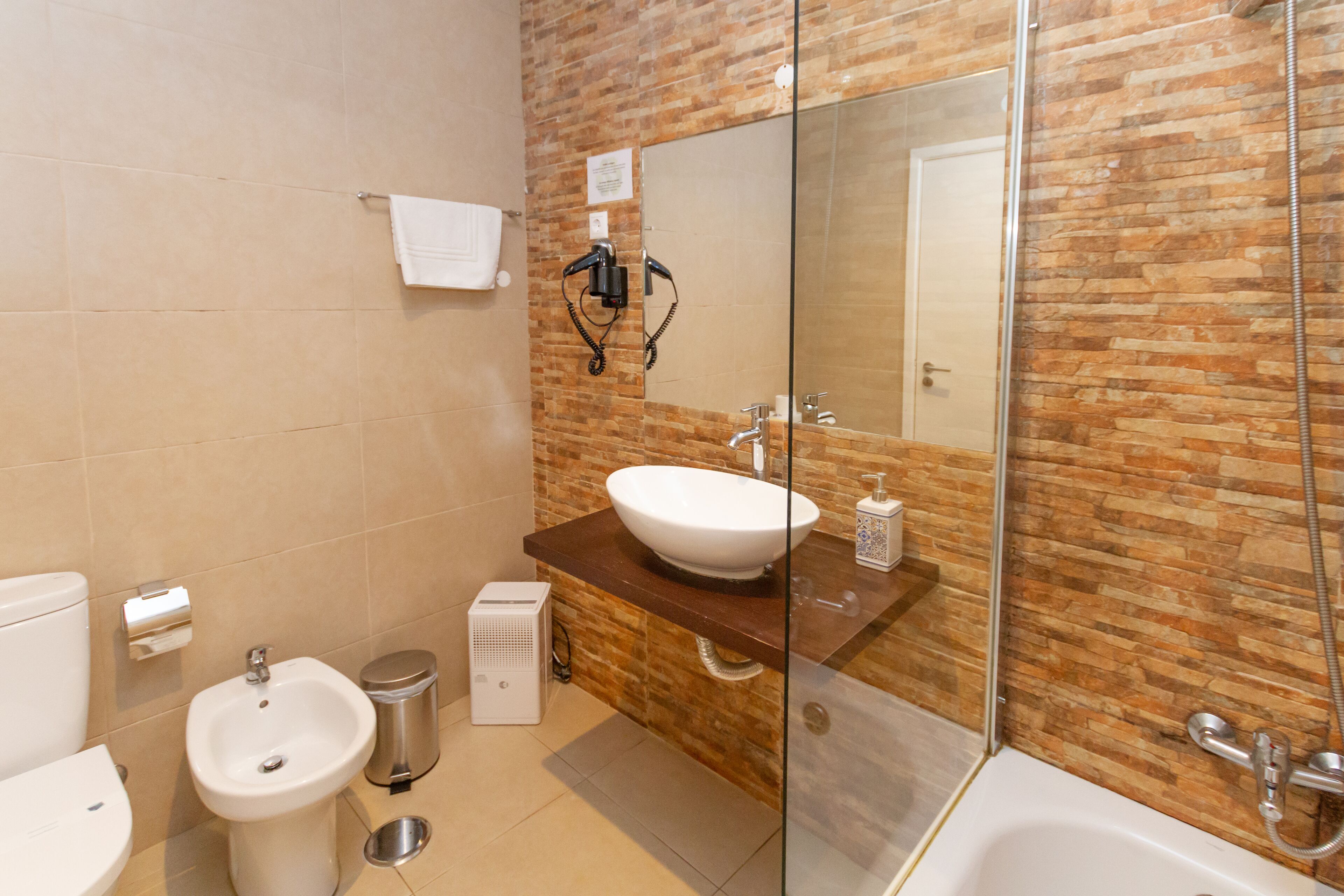 A modern bathroom with a large sink, bidet, and bathtub.