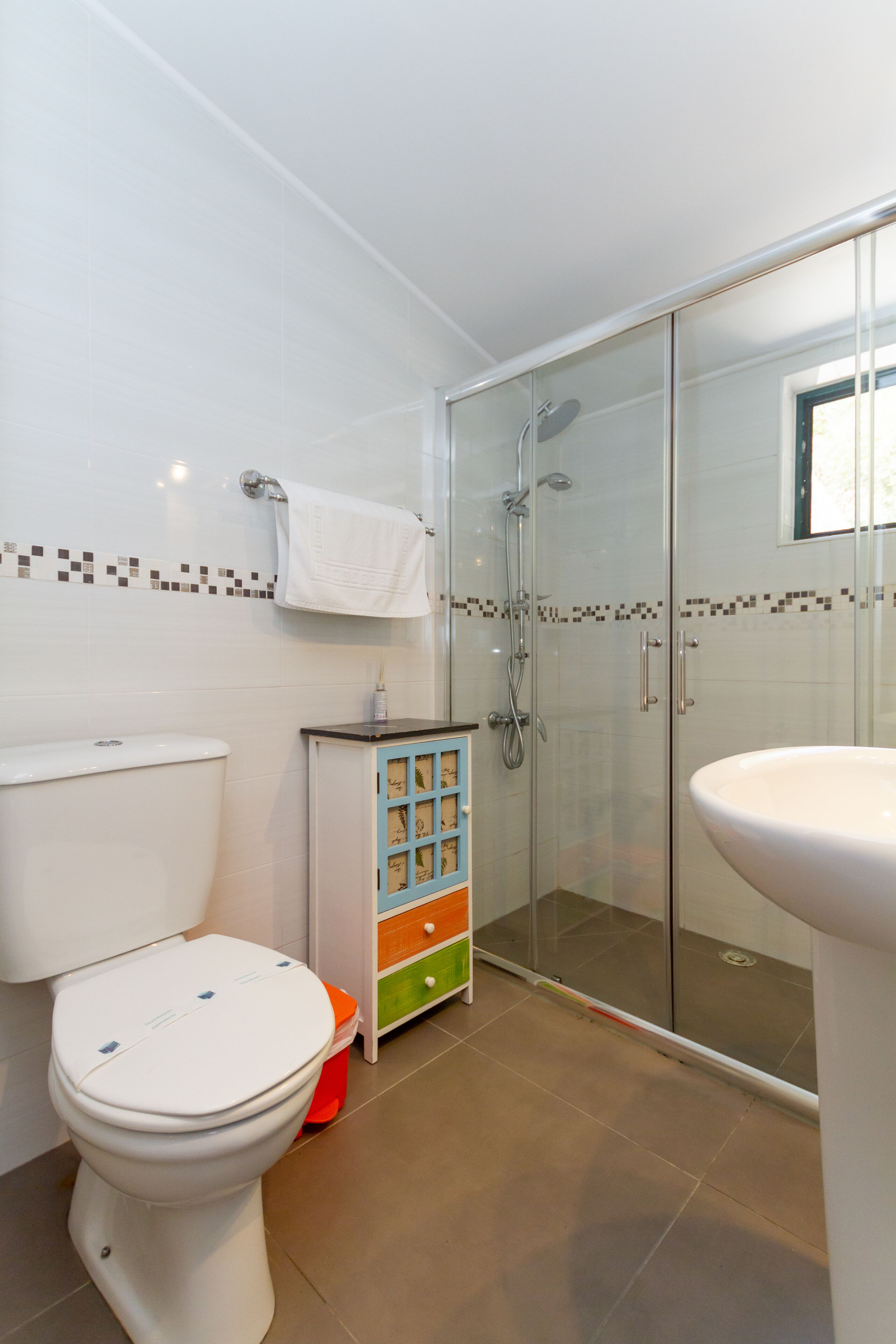 Een badkamer met toilet, een douchecabine en een wastafel.