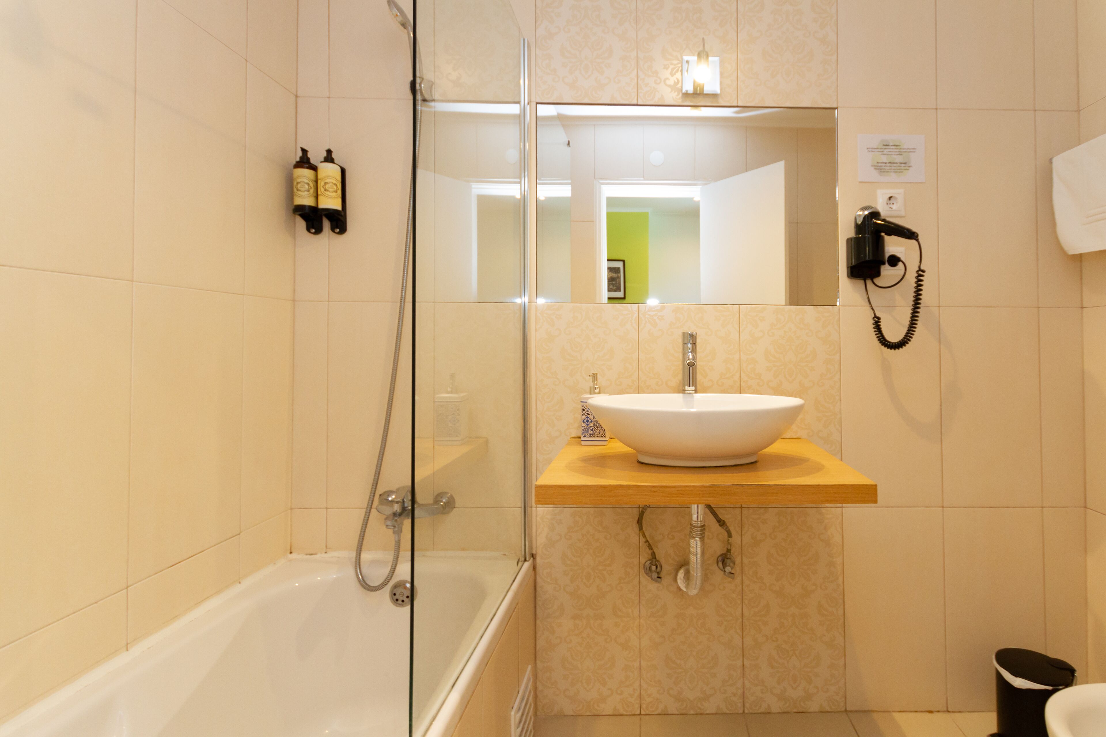 Un baño moderno con ducha envuelta en vidrio, un lavabo blanco sobre encimera de madera y un espejo sobre el lavabo.