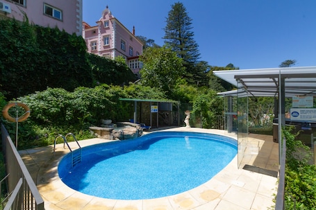 Una piscina al aire libre, sillones reclinables de piscina