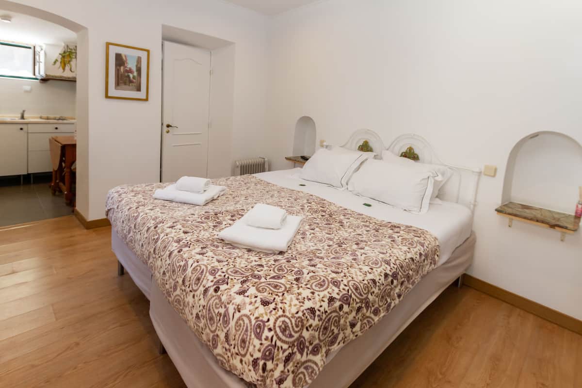 Ein Schlafzimmer mit einem Bett, einem Nachttisch, einem Sessel, einem kleinen Tisch und einer Tür.
