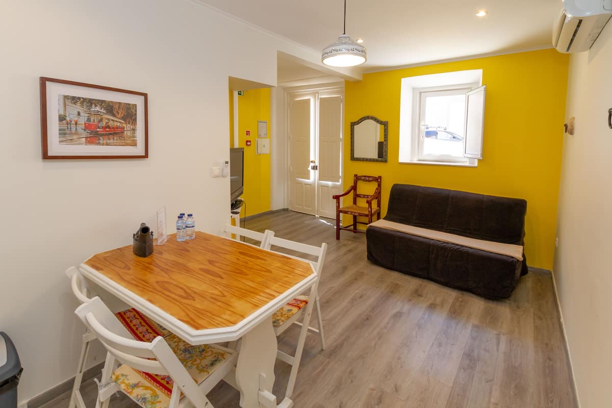 Ein Essbereich mit Holztisch und -stühlen, einer Couch und einem gerahmten Bild an der Wand.
