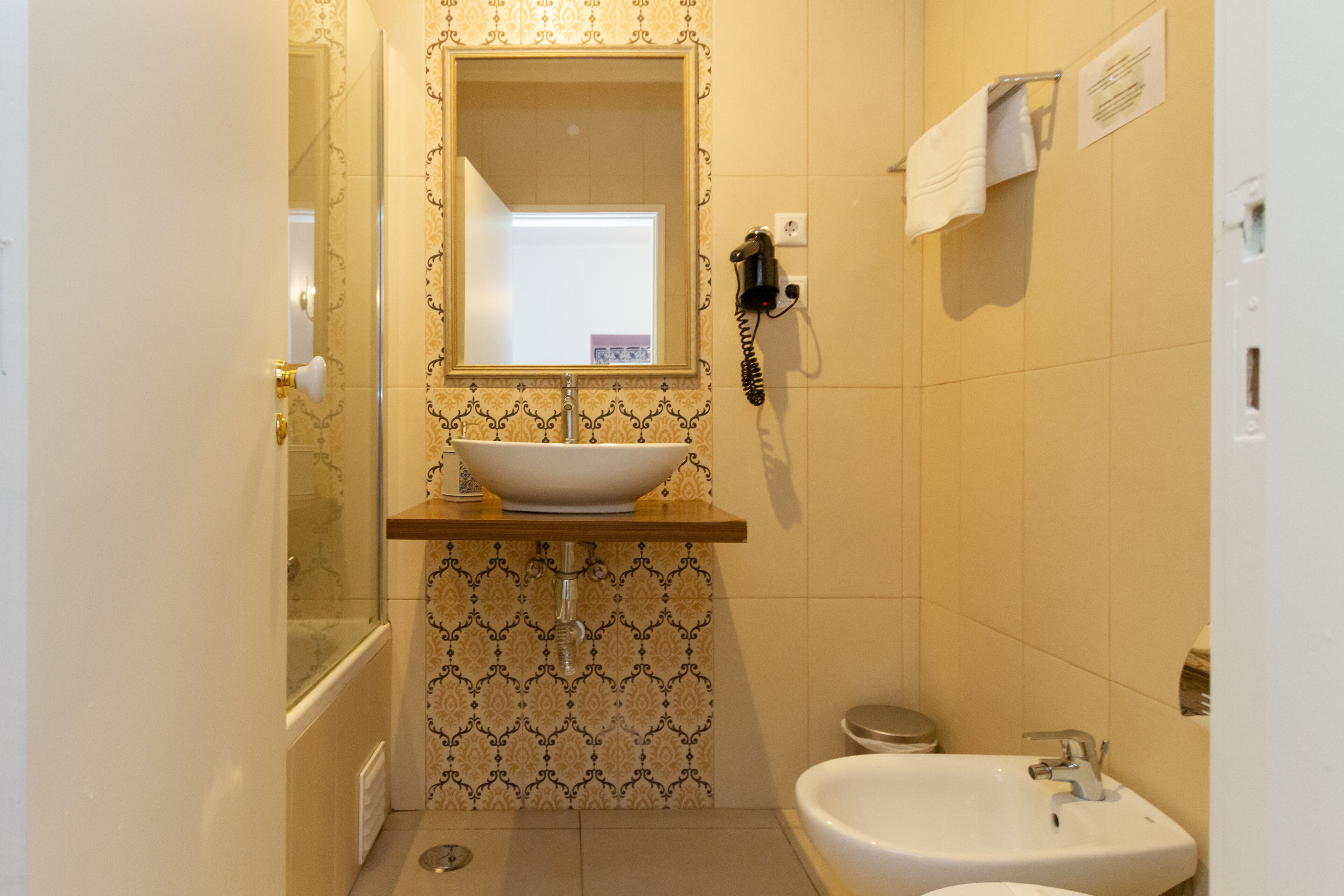 A bathroom with a sink, mirror, and a telephone.
